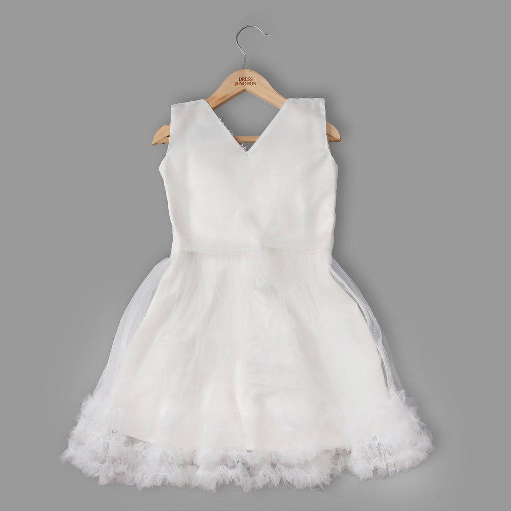 White dress with a tulle skirt on a wooden hanger against a gray background