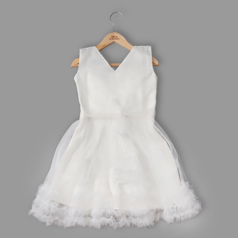 White dress with a tulle skirt on a wooden hanger against a gray background