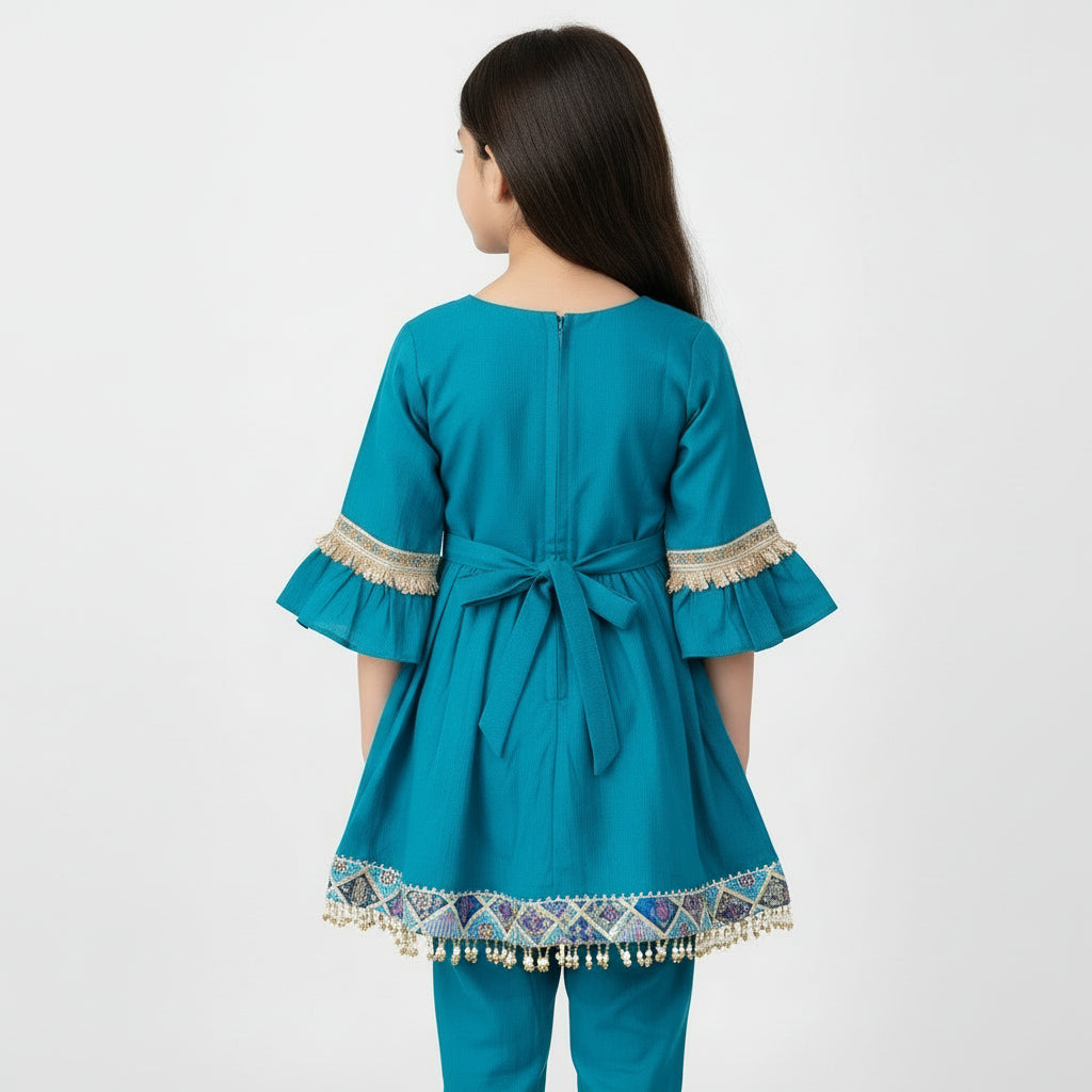 Teal children's outfit with decorative trim on a gray background