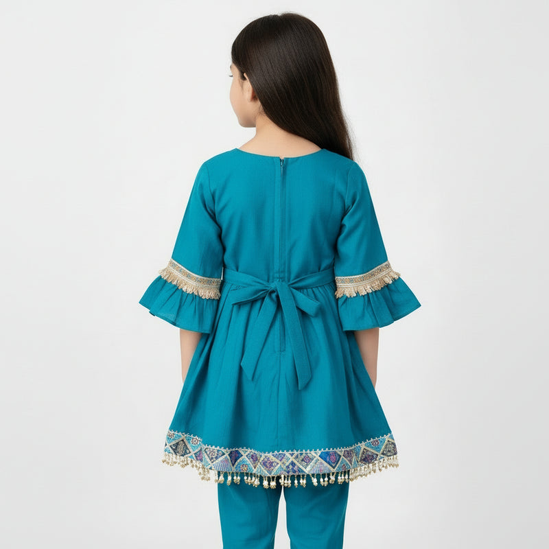 Teal children's outfit with decorative trim on a gray background