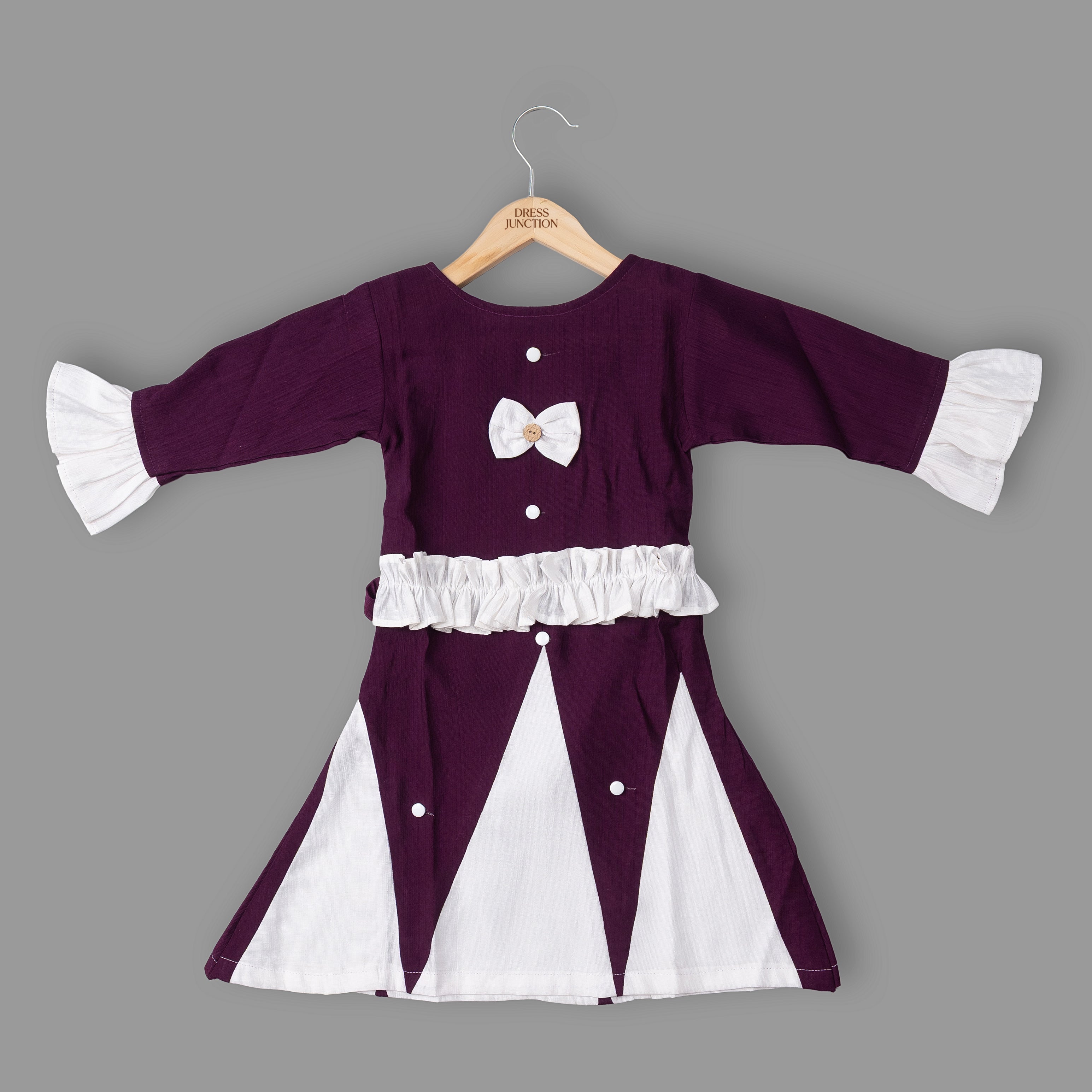 Purple and white dress with ruffled sleeves on a hanger against a gray background