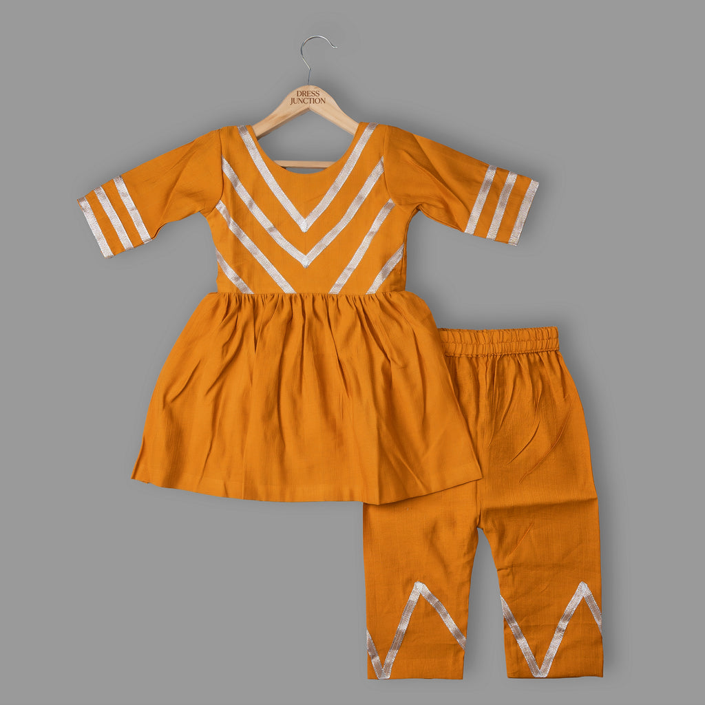 Orange children's outfit with white patterns on a gray background