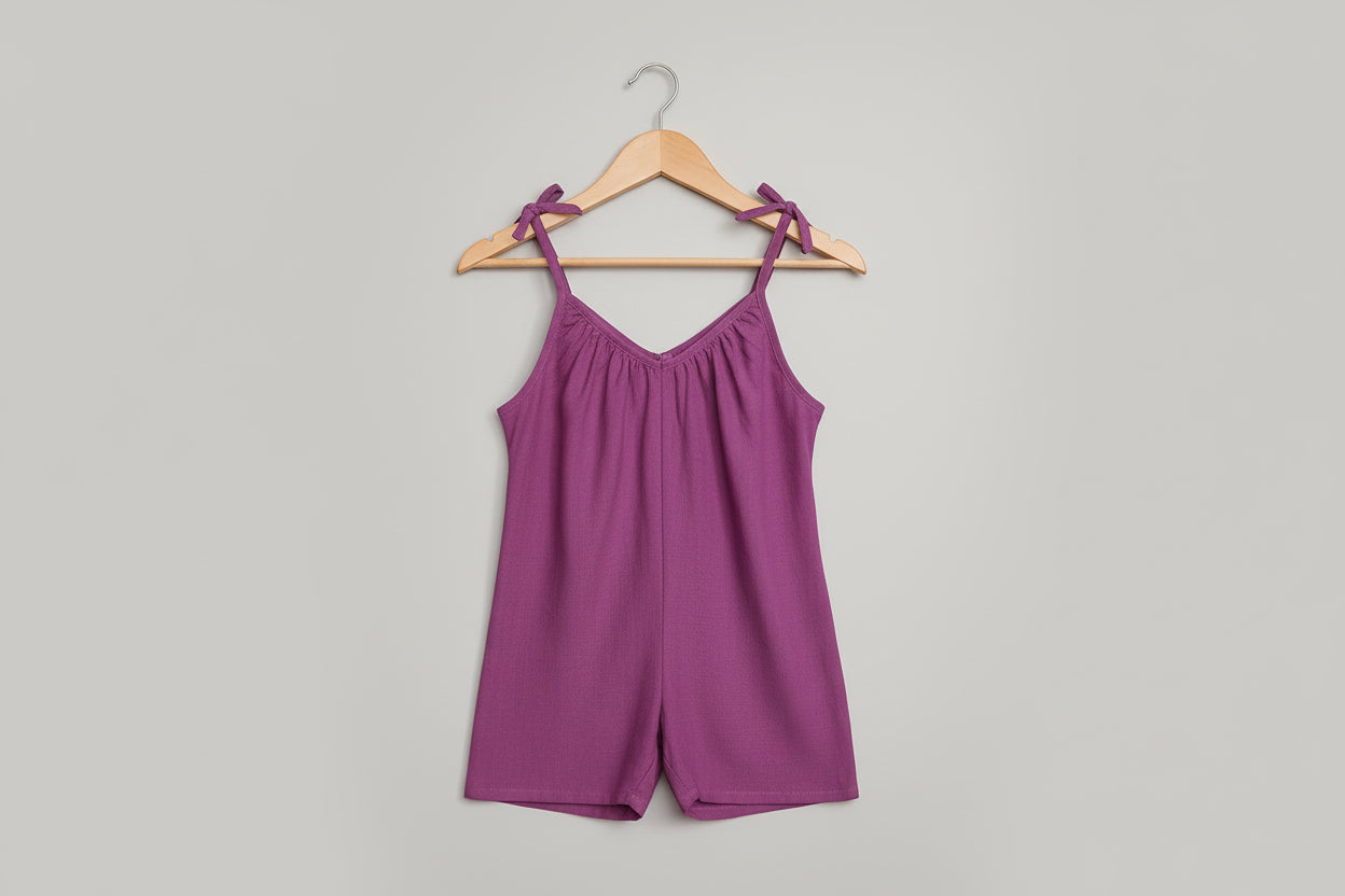 Purple romper with tie straps on a light gray background